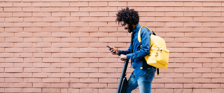 Ein Mann auf auf einem E-Roller mit Smartphone