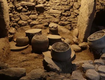 Steingefäße, Platten und Klopfsteine in Fundlage in einem Küchenbereich in Karahantepe, 9400–8000 v.Chr.