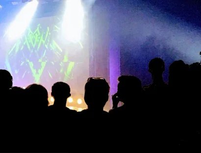 GRAFIK Menschen vor einer beleuchteten Bühne