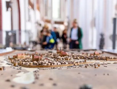 Modell der mittelalterlichen Stadt Berlin im Museum Nikolaikirche, im Hintergrund unscharf Besucher und das Innere des Kirchenschiffs