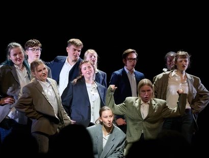 Eine Gruppe junger Menschen posieren in grauen und bauen Anzug-Sakkos.
