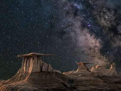 Die Oberfläche eines Planeten mit der Milchstraße im Hintergrund.