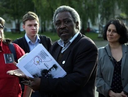 Ein Mann erklärt einer Gruppe von Menschen etwas, er hält einen Schnellhefter in den Händen