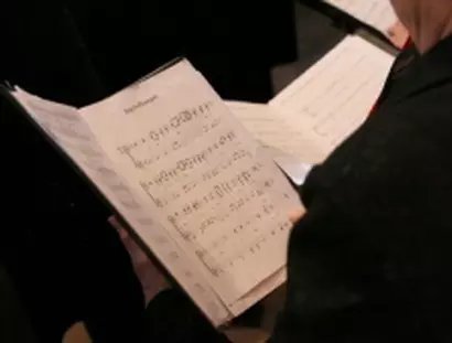 Singende Person hält ein Notenblatt