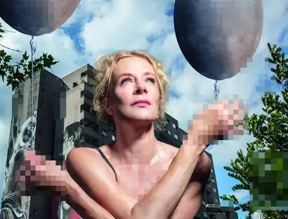 Katja Riemann sitzt unbekleidet in der Hocke vor einem Plattenbau und hält jeweils einen gräulichen Luftballon in den Händen. Die Hände, der Brust- und Intimbereich sind verpixelt.