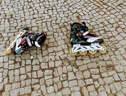 Zwei Inlineskater liegen auf Pflastersteinen