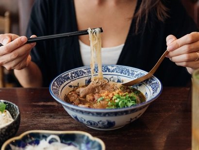 Eine Frau isst eine Nudelsuppe