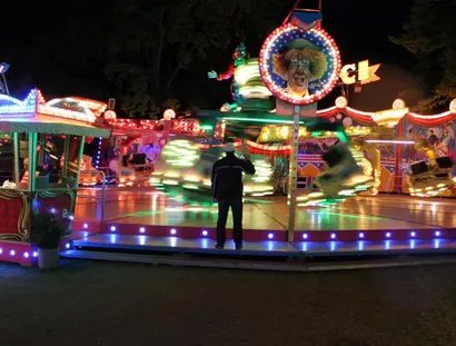 Beleuchtetes Fahrgeschäft auf einem Rummel am Abend