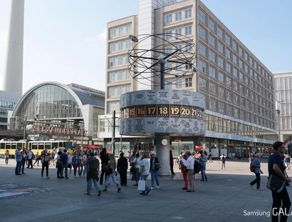 Menschen vor der Weltzeituhr am Alexanderplatz in Berlin
