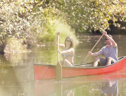 Couple rowing canoe on river