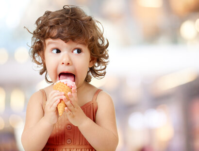 Kid eating ice cream. Funy curly child with icecream.