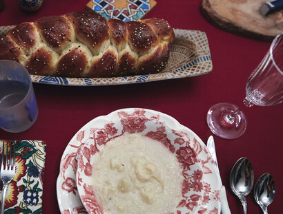 Overhead shot of a table with a loaf of challah and a plate on it.