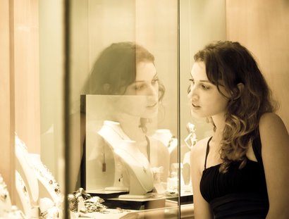 Young woman looks into glass case where jewelry is