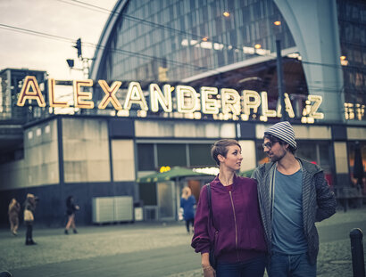 Una joven pareja frente a la estación de S-Bahn de Alexanderplatz al atardecer
