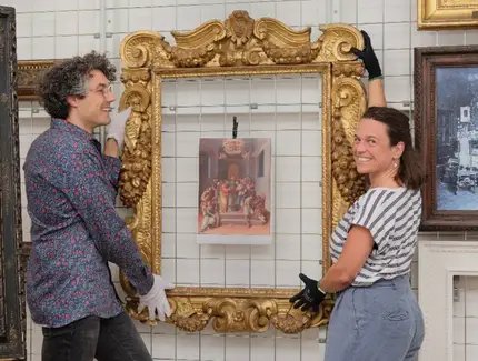 Blick in das Rahmenrestaurierungsatelier. Bertram Lorenz (li.) und Nadin Radecke (re.) stehen vor dem Sansovino-Rahmen.