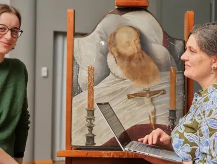 Marie Becker (li.) und Kerstin Krainer (re.) vor dem Gemälde Bildnis eines toten Mannes von Bartholomäus Bruyn d. J. während der Restaurierung.