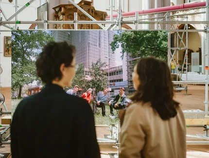 Blick über die Schulter zweiter Besucherinnen auf einen Film-Monitor im Museum