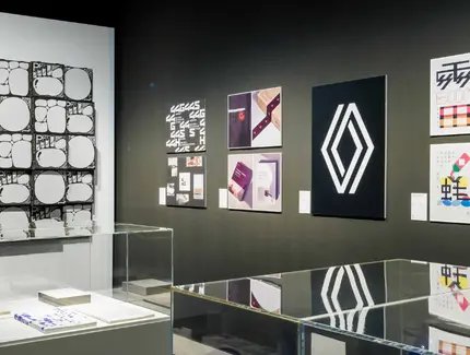 Blick auf an Wänden gehängte Plakate und Vitrinen mit Objekten im Vordergrund Blick auf an Wänden gehängte Plakate und Vitrinen mit Objekten im Vordergrund