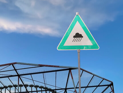Fotografie eines dreieckigen Schildes. In der Mitte ist ein Piktogramm einer Regenwolke abgebildet.