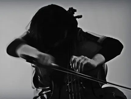 Schwarz-weiß-Bild mit leicht verschwommenen Konturen: Eine Person spielt Cello.