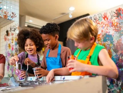 Fröhliche Kinder gestalten mit Farbe in einem Werkraum.
