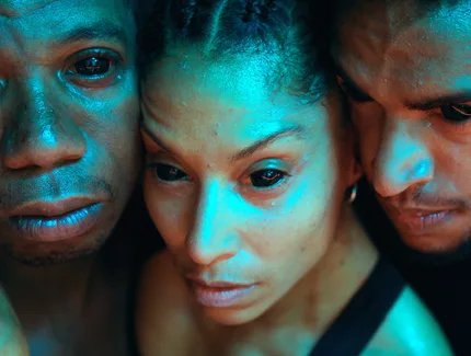 Close up auf die Gesichter von drei People of Colour. Sie haben tote Augen und blicken traurig.