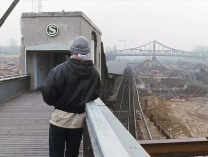 Mann auf Brücke mit S-Bahn-Eingang blickt über eine Baustelle auf eine Brücke