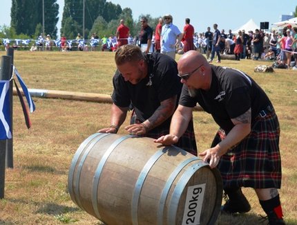Zwei Männer im Kilt rollen ein 200 Kilogramm Fass