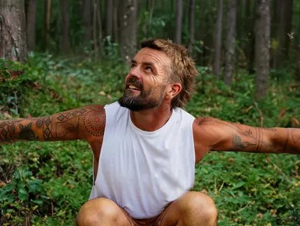 Xavier Rudd in einem Wald hockend