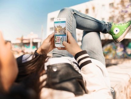 Junge Frau nutzt Streetart Highlight der ABOUT BERLIN App.