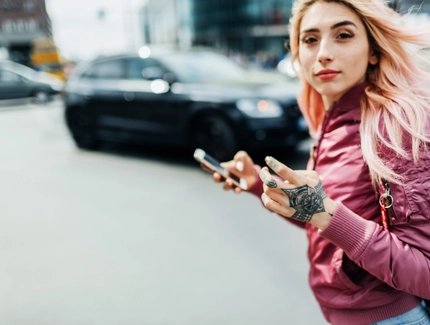 Junge Frau bewegt sich durch eine Stadt und hält ein Smartphone in der Hand