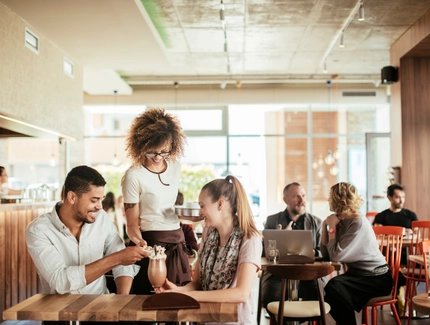 A waitress serves a couple in a café in Berlin In the café