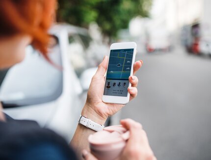 Compartir coche: una mujer en Berlín usa una aplicación en su smartphone