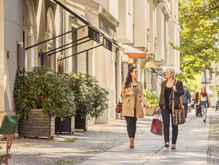 Two women walking on the pavement after shopping or strolling 