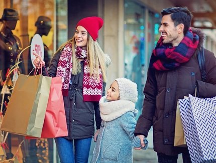 Parents and child strolling happily by the shop window in winter and smiling