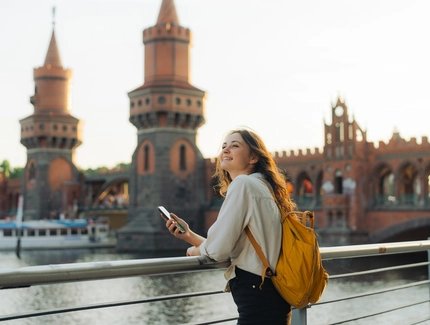 Junge Frau mit Smartphone vor der Oberbaumbrücke