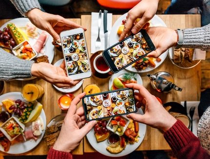 Friends taking pictures of food on the table with smartphones during brunch in restaurant