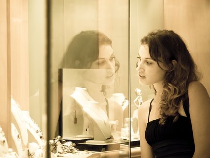 Young woman looks into glass case where jewelry is