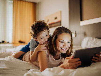 La madre y el niño se acuestan en la cama y miran una tableta
