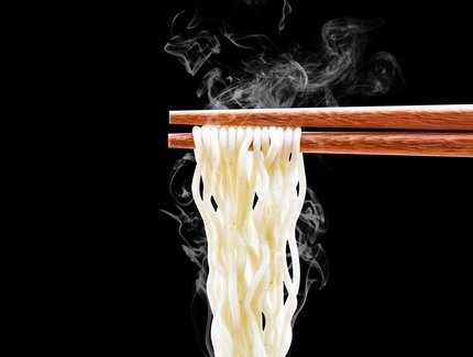 Noodles with chopsticks against a black background 