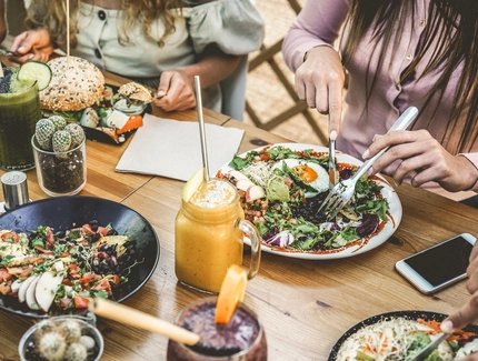 Hands view of young people eating brunch and drinking smoothies bowl with ecological straws in plastic free restaurant - Healthy lifestyle, food trends concept - Focus on top fork dish