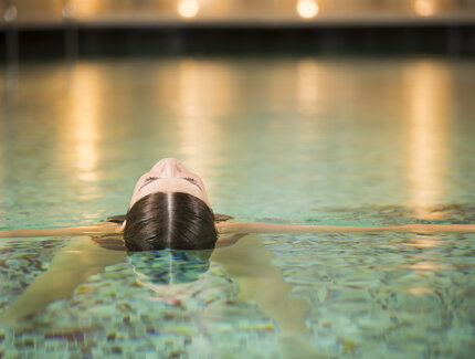 Eine Frau entspannt sich im Pool eines Day Spa
