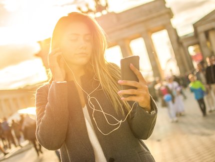 Young woman listening to audio tour at Brandenburg Gate.