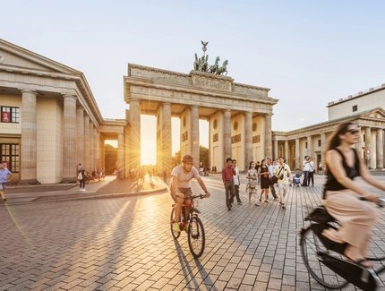 Berliner Sehenswürdigkeit Brandenburger Tor im Sonnenlicht mit Radfahrern