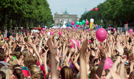 jubelnde Menschen bei Sportveranstaltung in Berlin Tiergarten mit Blick auf das Brandenburger Tor