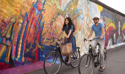 Pärchen auf Fahrrädern an der East Side Gallery