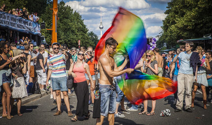 La gente con la bandera del arco iris en el Pride Parade en Berlín