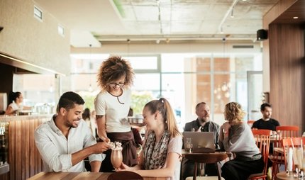 Im Café Eine Kellnerin bedient ein Paar im Café in Berlin