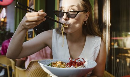 Frau_isst_im_Restaurant_mit_Stäbchen_asiatisch