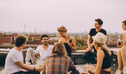 Freunde treffen sich über den Dächern Berlins, lachen zusammen und haben spaß